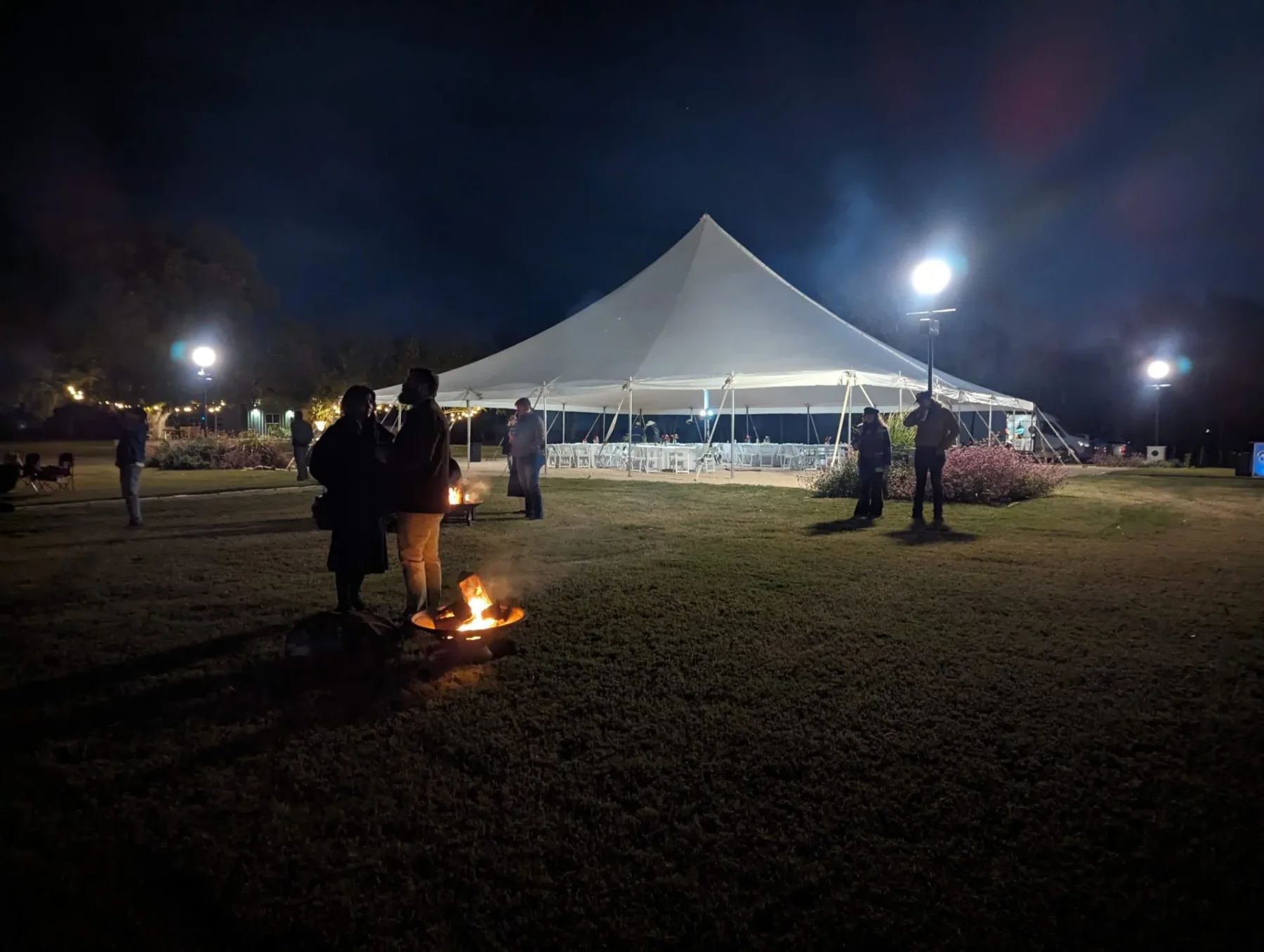 An event tent arranged in the gardens at night
