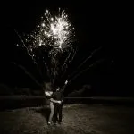 A couple embrace as they watch fireworks over the lake